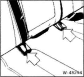 • Снимите подушку заднего сиденья Для этого сначала удалите заглушки на накладках ремней безопасности (указаны стрелками) с помощью отвертки.